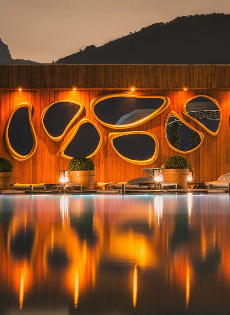 Luxurious rooftop pool overlooking Ipanema Beach, with sleek modern design and panoramic Rio de Janeiro skyline at sunset