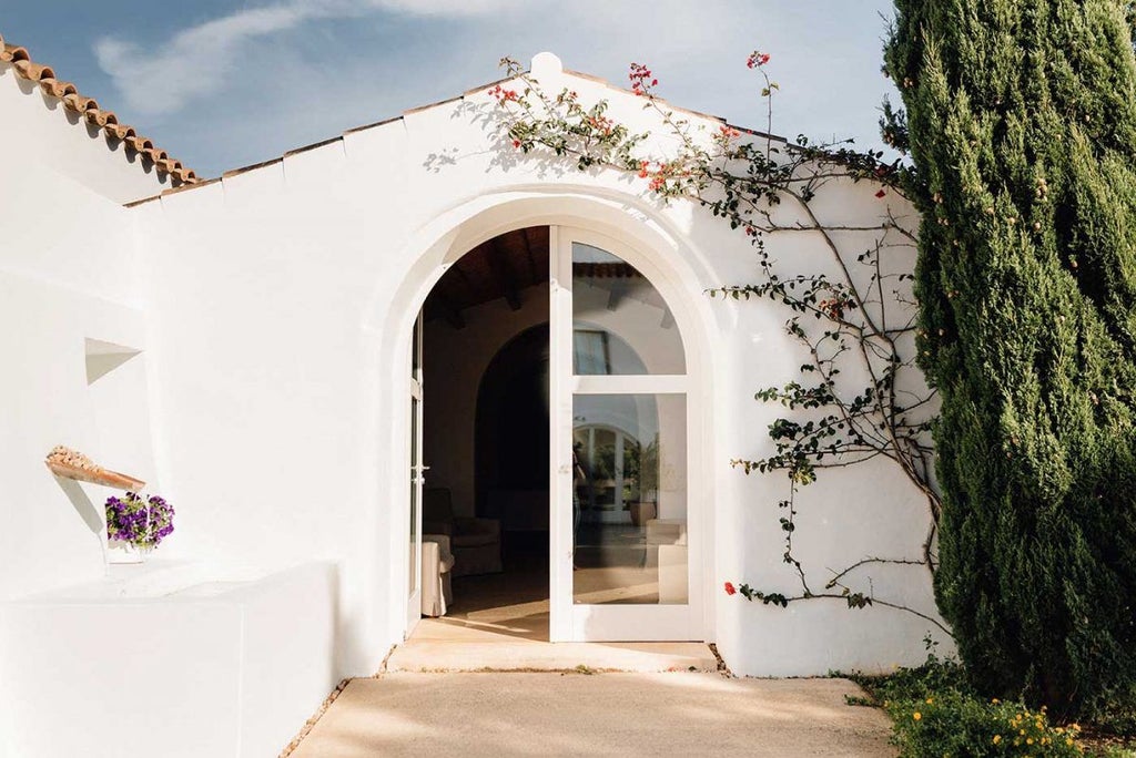 Luxury whitewashed Mediterranean hotel nestled on Menorca coastline, rustic stone walls, elegant terrace overlooking azure waters and rolling countryside landscape