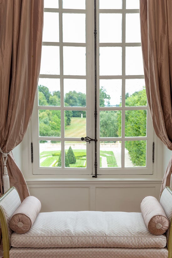 Elegant corner king room with floor-to-ceiling windows overlooking French gardens, featuring ornate antique furniture and crystal chandelier