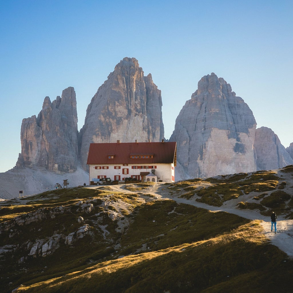 Majestic snow-capped Dolomites mountain peaks rising above lush alpine meadows, with traditional timber chalets nestled in the valley