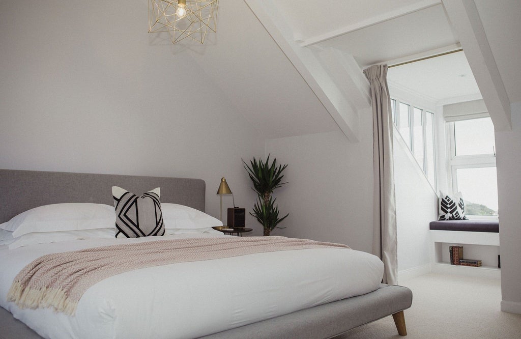 Elegant neutral-toned bedroom with plush white bedding, contemporary wooden headboard, and soft ambient lighting in a luxurious UK countryside accommodation