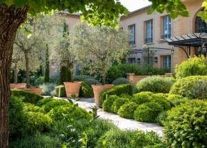 Luxurious stone villa with blue shutters nestled in French countryside, surrounded by lavender fields and verdant cypress trees at golden hour