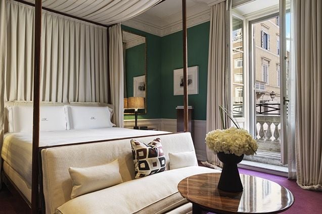 Elegant balcony room at luxury designer hotel in Roma, featuring plush white bedding, classic Italian decor, and soft natural light streaming through French doors