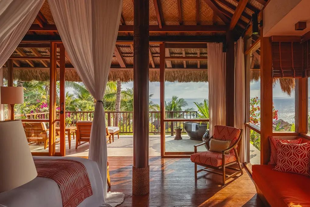 Luxurious open-air wooden suite with sweeping ocean views, traditional Indonesian design, and private terrace overlooking lush tropical landscape at NIHI resort, Sumba