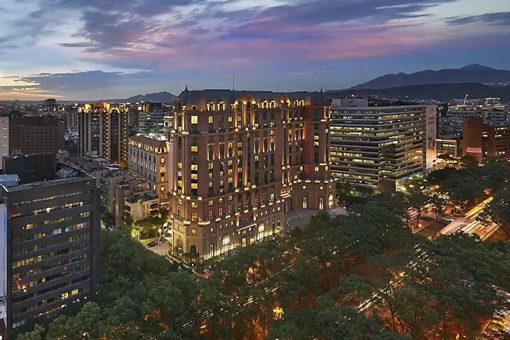 Elegant facade of luxury hotel featuring grand entrance with ornate pillars, cream-colored stonework and outdoor mood lighting at dusk