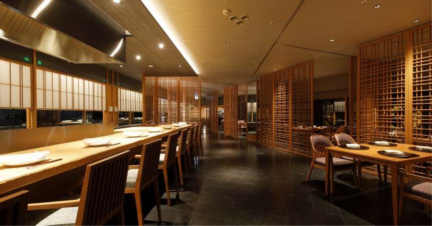 Towering glass facade of Hotel Nikko Tokyo illuminated at twilight, reflecting cityscape with sleek modern architecture and ambient lighting