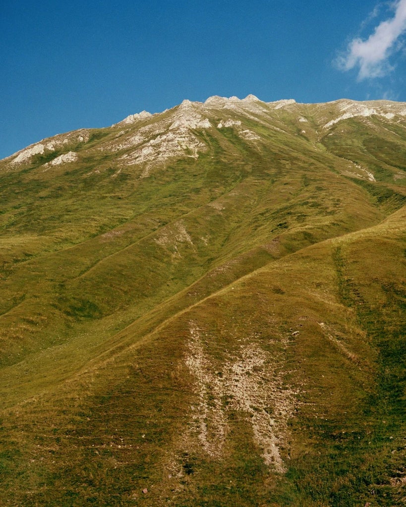 Luxurious mountain hotel nestled in scenic Georgian landscape, featuring modern architecture with expansive windows and stunning alpine backdrop of Kazbegi region