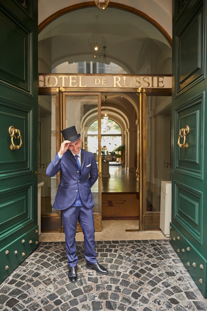 Elegant courtyard garden at Hotel de Russie Rome featuring manicured hedges, stone terraces, and al fresco dining beneath lush greenery