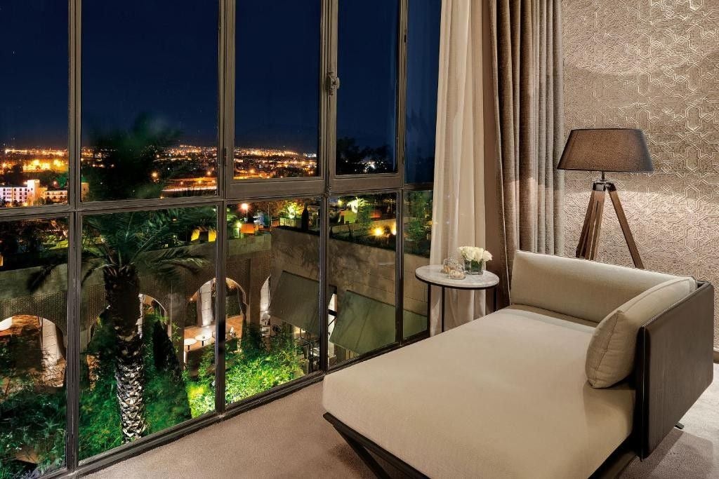 Modern rooftop infinity pool overlooking Fez cityscape at sunset, with elegant lounge chairs and Moroccan architectural details visible