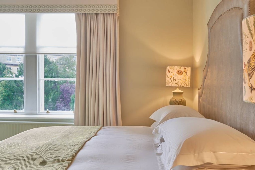 Luxurious king-sized bed with plush white linens, elegant contemporary design, soft neutral tones, and minimalist wooden furniture in a cosy UK hotel room