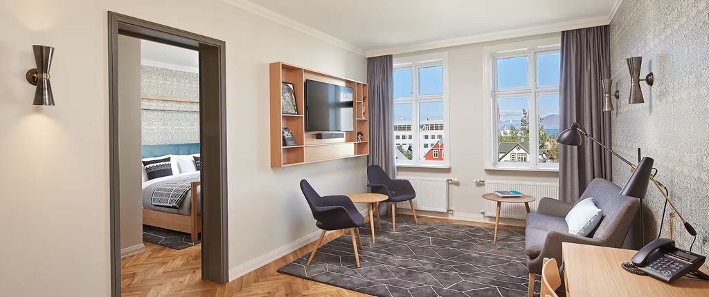 Modern Nordic hotel exterior with glass facade, wooden accents, and sleek geometric design nestled in downtown Reykjavik at sunset