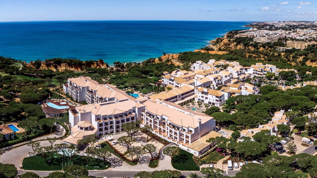 Elegant Portuguese hotel featuring whitewashed walls, red-tiled roofs, and manicured gardens perched atop dramatic orange cliffs by the sea