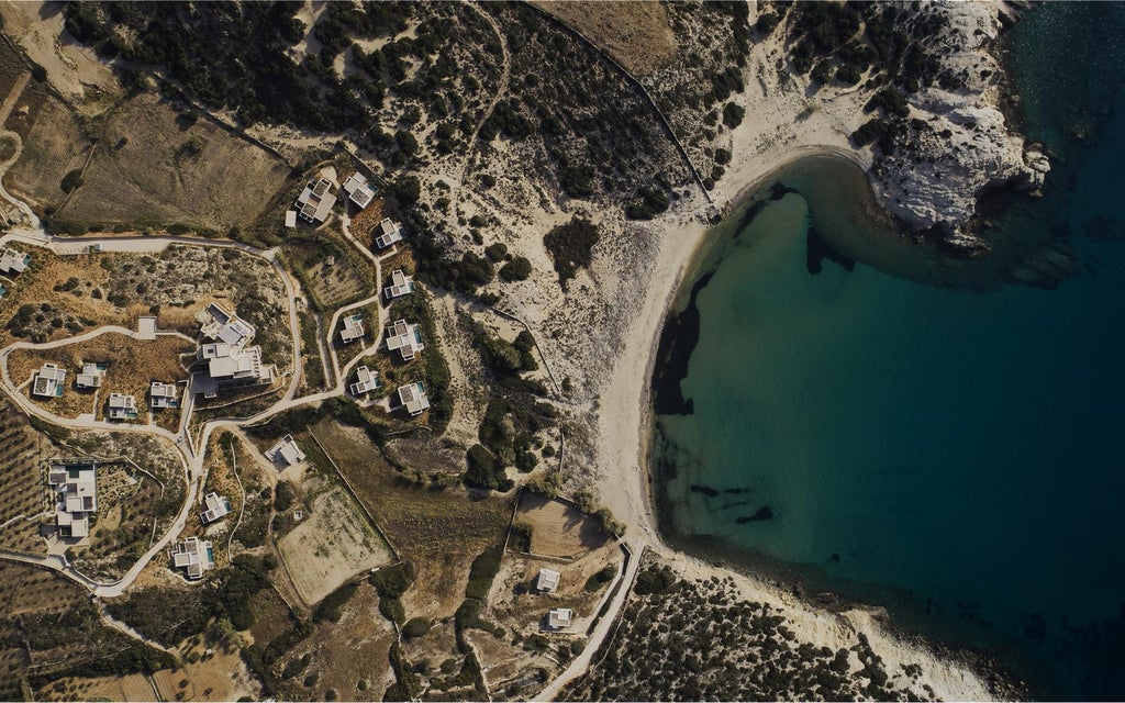 White minimalist luxury resort with stone walls, infinity pool overlooking the Aegean Sea, surrounded by arid Greek landscape