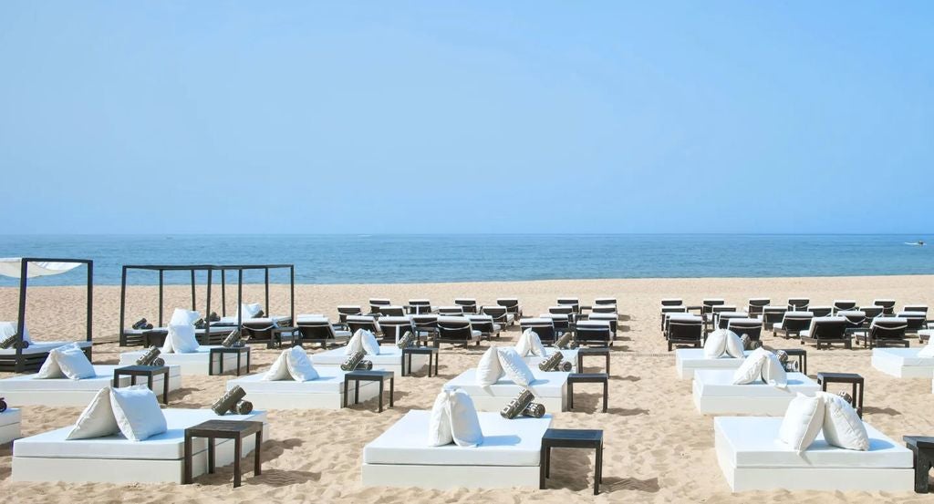 Elegant pool terrace of Anantara Vilamoura resort with white loungers, palm trees and Mediterranean architecture at sunset