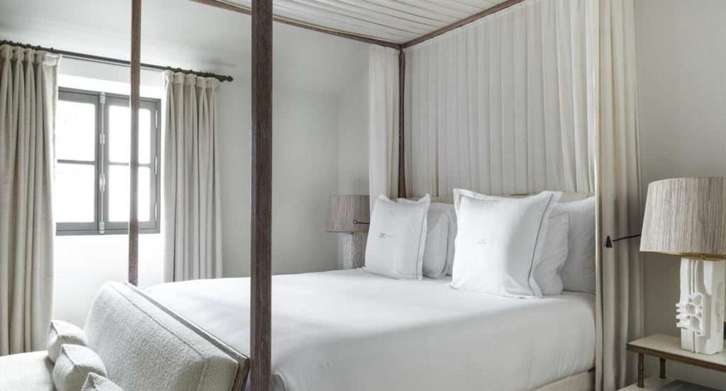 Elegant Parisian hotel junior suite with plush white bedding, soft neutral tones, modern minimalist design, and chic decorative accents highlighting luxury accommodation