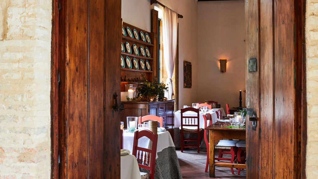 Historic Spanish hacienda with whitewashed walls, terracotta roof tiles, and elegant courtyard featuring manicured gardens and al fresco dining