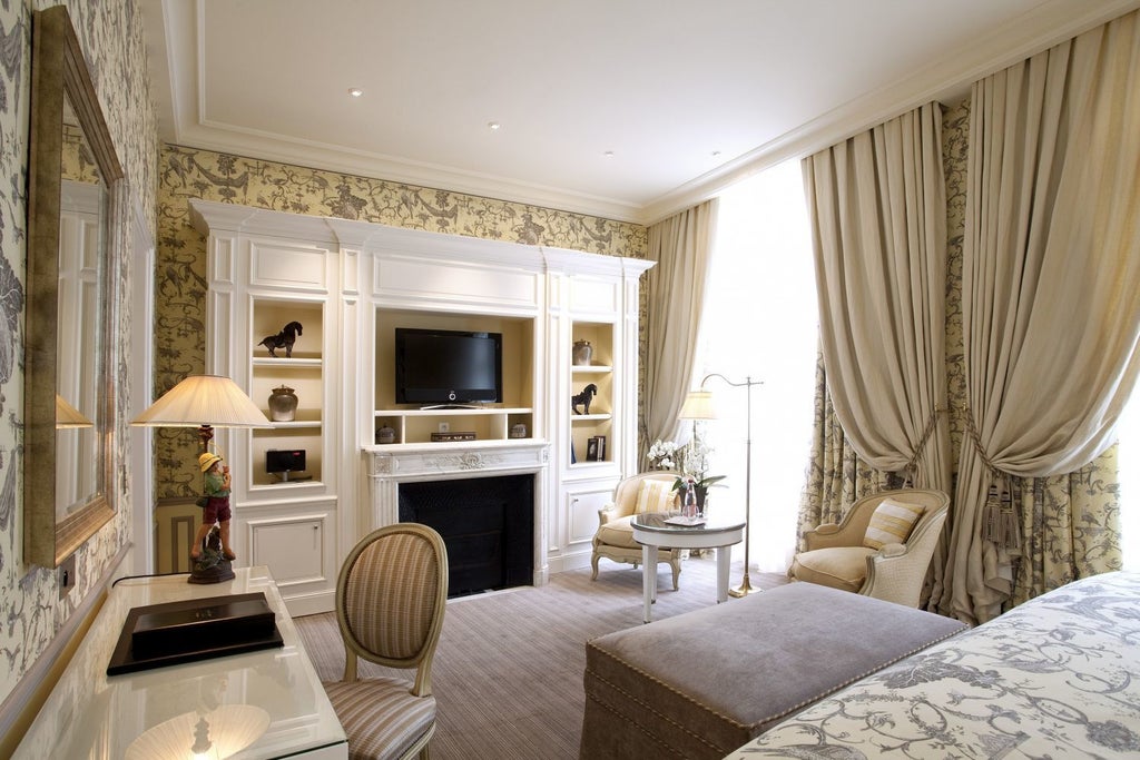 Opulent French hotel room with crystal chandelier, antique furnishings, fireplace, and floor-to-ceiling windows draped in silk curtains