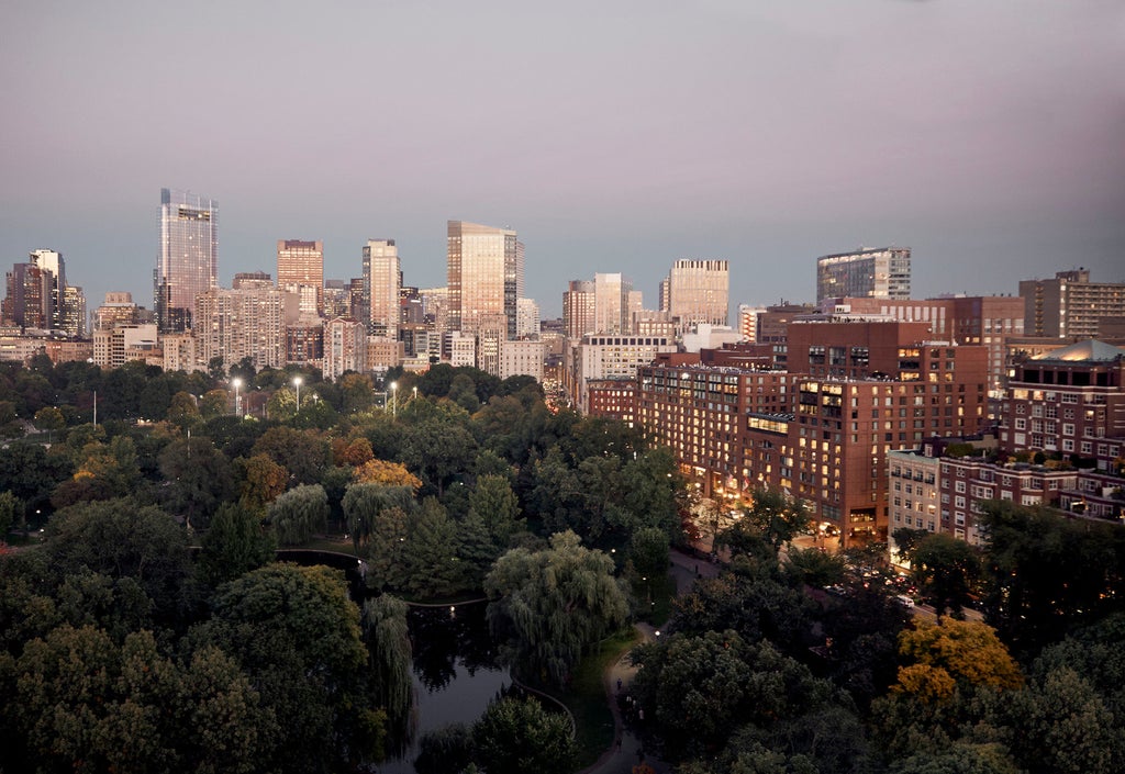 Elegant Four Seasons Boston hotel exterior with glass facade, manicured gardens, and grand circular driveway under warm evening light