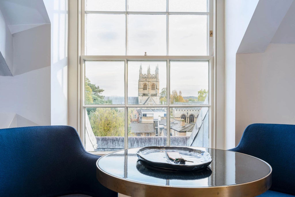 Elegant superior deluxe hotel room with private balcony, featuring classic British design, rich wooden furnishings, and pristine white linens at Old Bank Hotel.