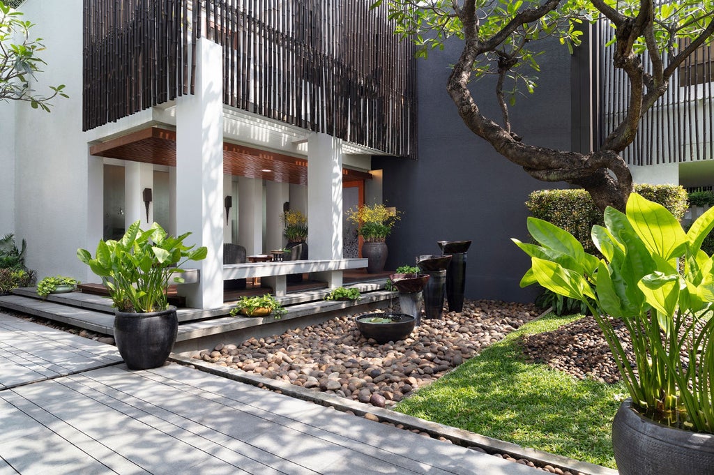 Elegant Thai-style hotel lobby with ornate wood pillars, traditional art, soft lighting and plush seating overlooking serene lotus ponds