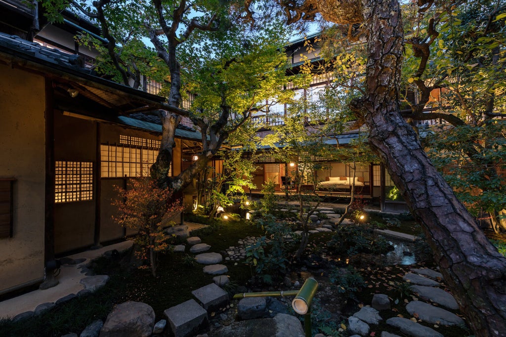 Traditional Japanese ryokan entrance with stone path, lanterns, wooden gates, and manicured bonsai trees at Luxury Hotel Sowaka, Kyoto