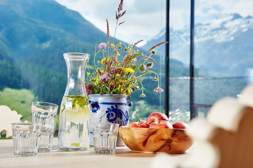 Modern luxury hotel nestled in Austrian Alps with wood-paneled facade, floor-to-ceiling windows and mountain backdrop at golden hour