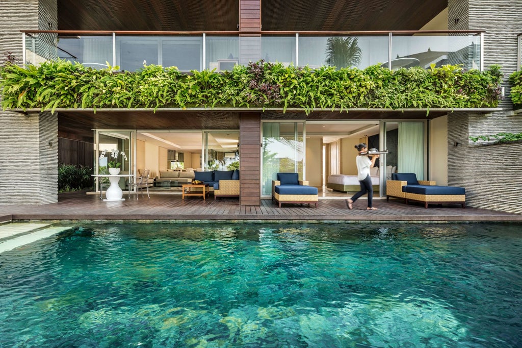 Modern beachfront infinity pool at luxury resort overlooking Canggu surf break, with ocean-view cabanas and swaying palm trees