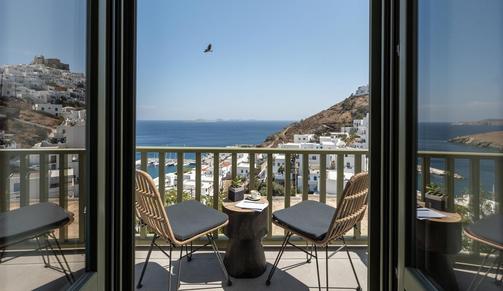 Luxurious white-washed Greek suites with blue accents overlooking Aegean Sea, traditional Cycladic architecture with elegant balconies and panoramic coastal views