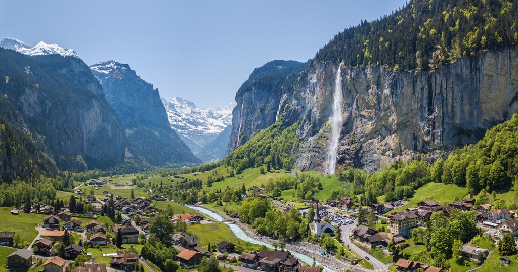 Dramatic Swiss Alps landscape with verdant meadows, towering limestone cliffs, and cascading waterfalls framing a serene hiking trail in Lauterbrunnen Valley