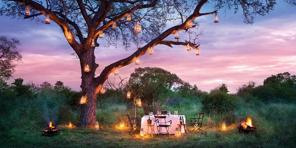 Luxurious safari lodge suite with private plunge pool overlooking Kruger National Park's savanna, featuring thatched roof and deck