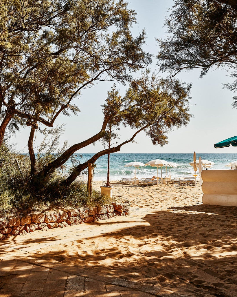 Rustic luxury Masseria in Puglia with stone walls, olive grove, and blue sea view, showcasing elegant Mediterranean countryside retreat