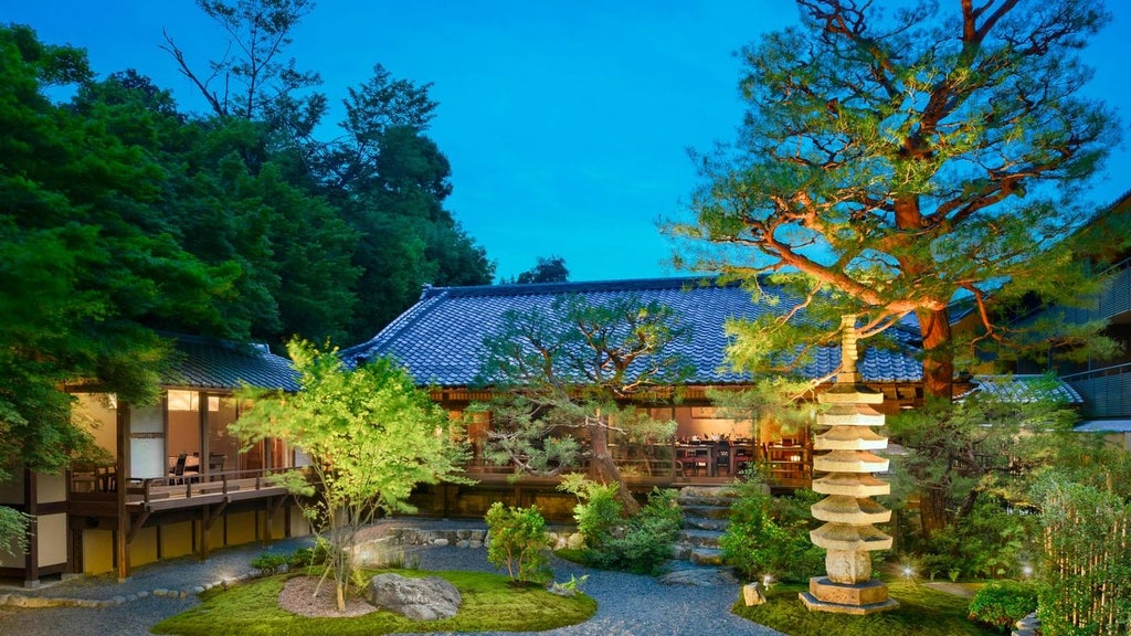 Elegant traditional Japanese ryokan-style luxury hotel with wooden architecture nestled alongside Kyoto's scenic Arashiyama riverside at twilight