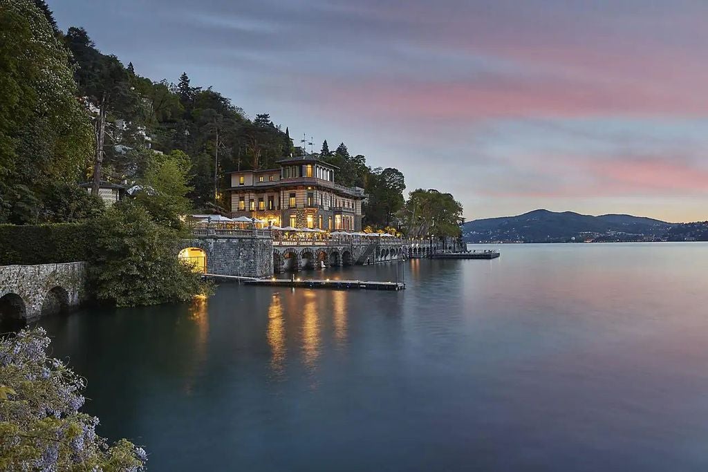 Luxurious waterfront hotel nestled against Italian Alps, featuring grand terraces overlooking Lake Como with elegant Mediterranean gardens