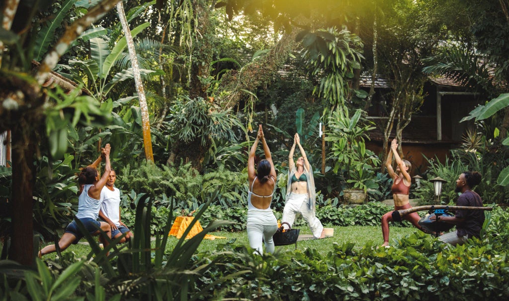 Luxurious Brazilian boutique hotel with rustic-chic design, tropical palm trees, and elegant white buildings nestled in lush Trancoso landscape