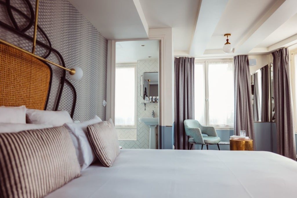 Elegant Parisian hotel room with plush white bedding, rich navy blue walls, vintage artwork, and sophisticated contemporary furnishings