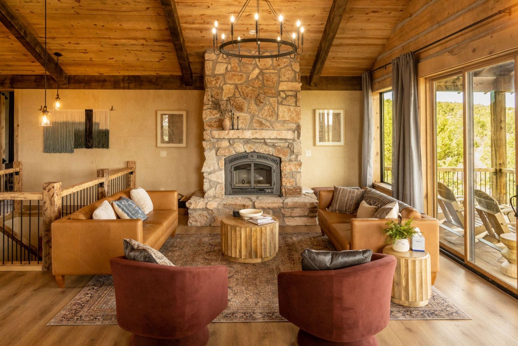 Rustic lodge room with wooden furnishings, plush bedding, and large windows overlooking scenic mountain landscape at Scenset Mountain Ranch in southwestern United States