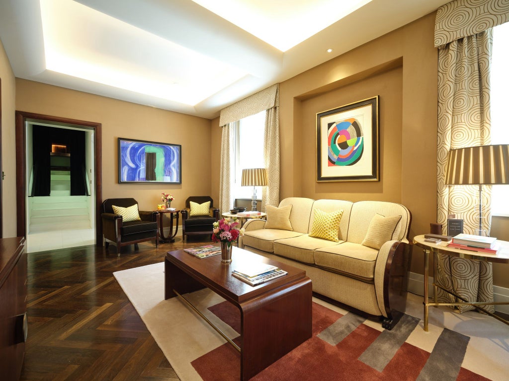 Minimalist luxury hotel room in Mayfair, London, with modern design, sculptural wooden furniture, and muted earth-toned textiles and lighting