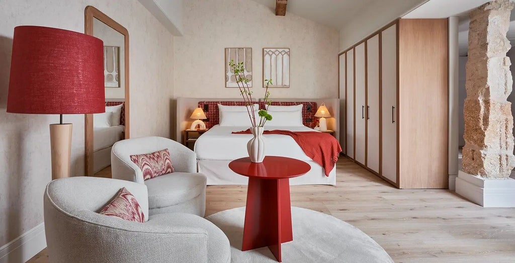 Elegant boutique hotel room in Palma, Spain, with warm wooden floors, white linens, and chic Mediterranean-inspired decor and furnishings