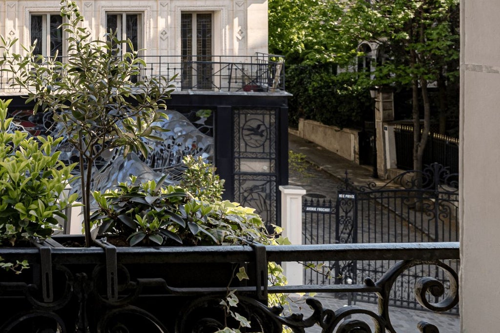 Elegant Parisian hotel room with soft blush pink walls, vintage-inspired decor, plush white bed, and classic French windows overlooking a charming street