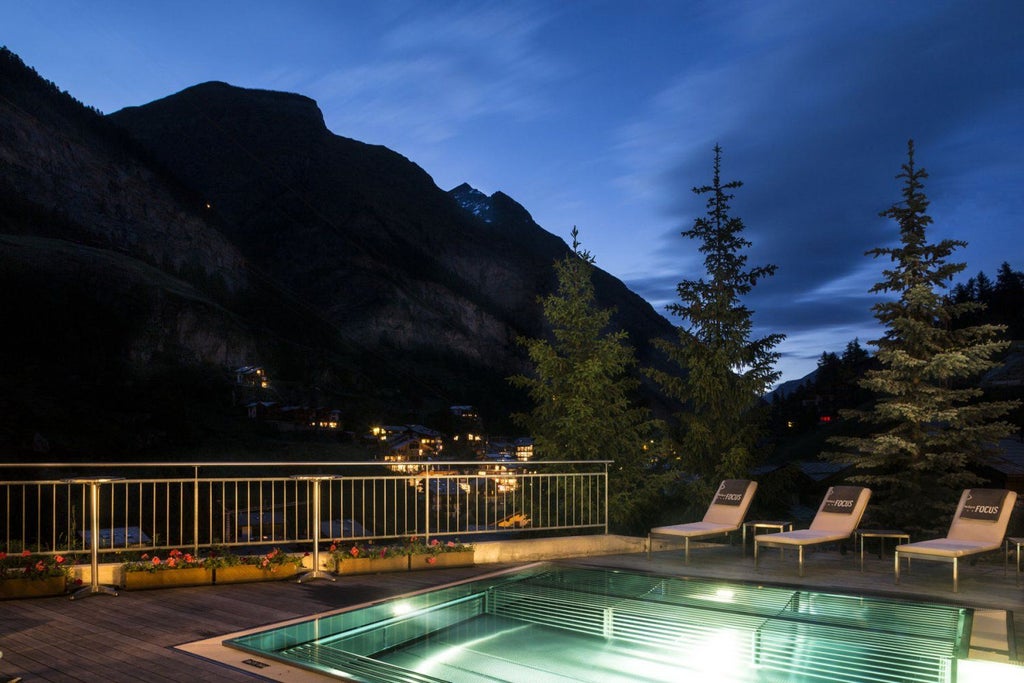 Modern alpine hotel featuring glass and wood facade with Matterhorn peak visible behind, luxury balconies overlooking snowy mountain landscape