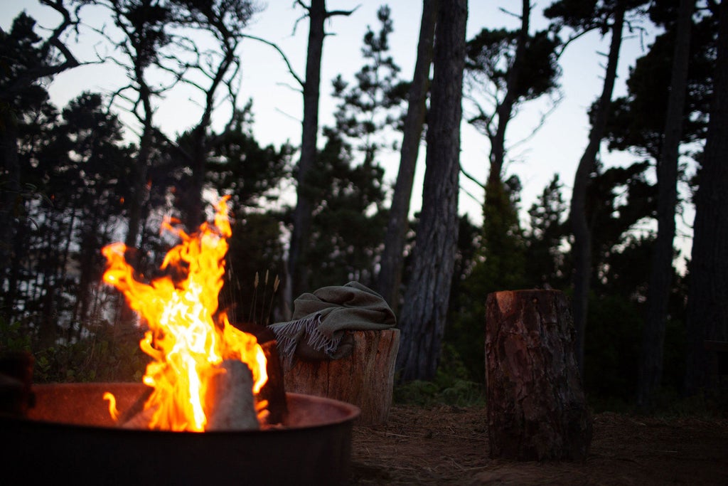 Luxury glamping tent nestled in redwood forest, featuring canvas walls, wooden deck, and modern outdoor furniture at Mendocino Grove