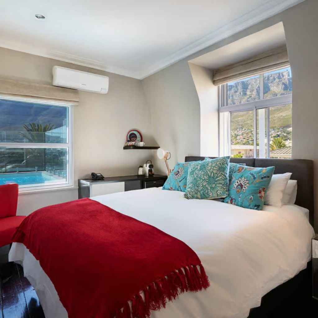 Modern luxury boutique hotel with white colonial-style balconies and wraparound terraces, set against backdrop of Table Mountain in Cape Town