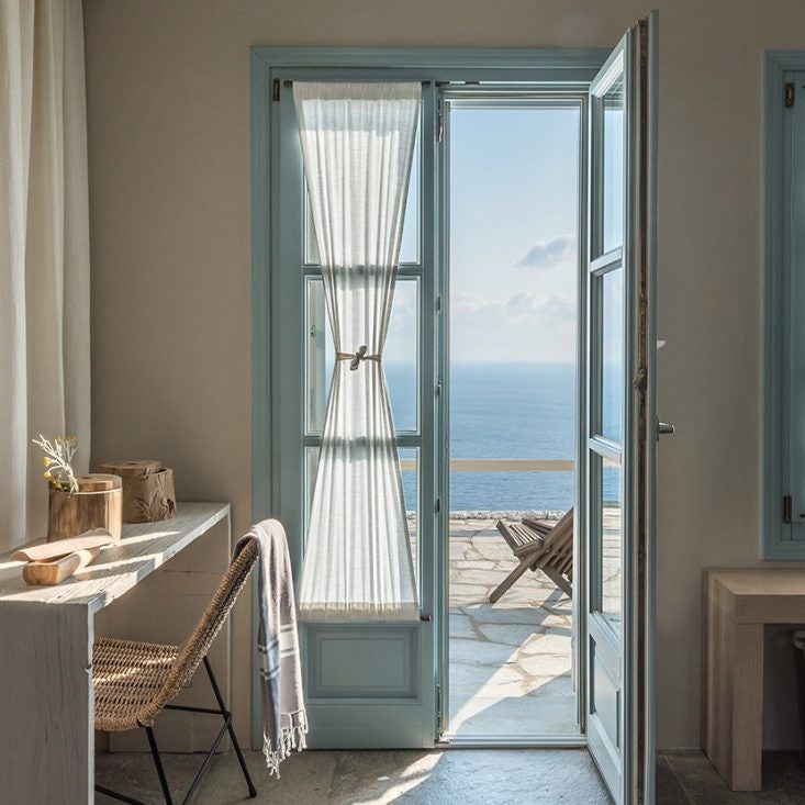 Luxurious whitewashed Cycladic hotel overlooking the azure Aegean Sea, with minimalist architectural design and stunning sunset views over Sifnos island landscape