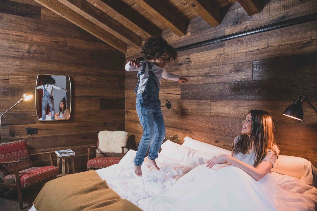 Cozy mountain lodge bedroom with rustic wooden furnishings, plush bedding, and panoramic alpine views of scenic Andorran landscape through large windows