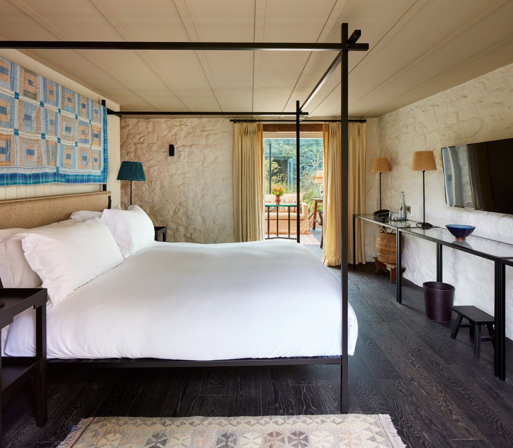 Elegant rustic bedroom with exposed wooden beams, plush white linens, and soft natural light illuminating a serene countryside retreat at Grove of Narberth.