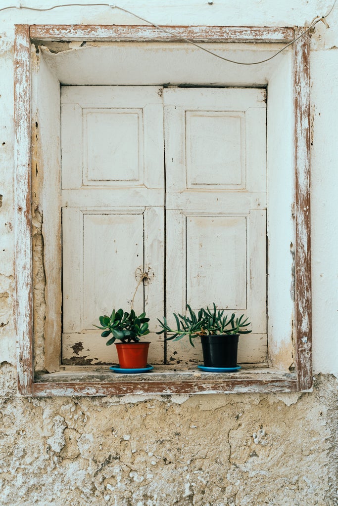 Whitewashed Italian villa in Puglia with curved archways, stone walls and flowering plants, set against vibrant blue sky at sunset