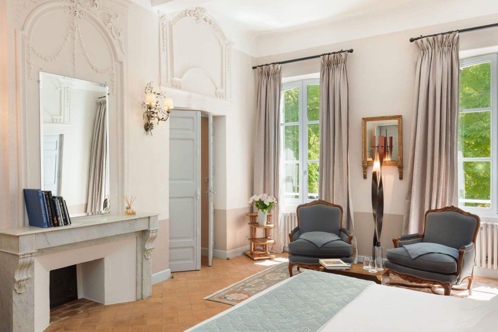 Elegant stone-walled hotel room with antique wooden furnishings, soft lighting, and luxurious French provincial decor in a historic abbey setting