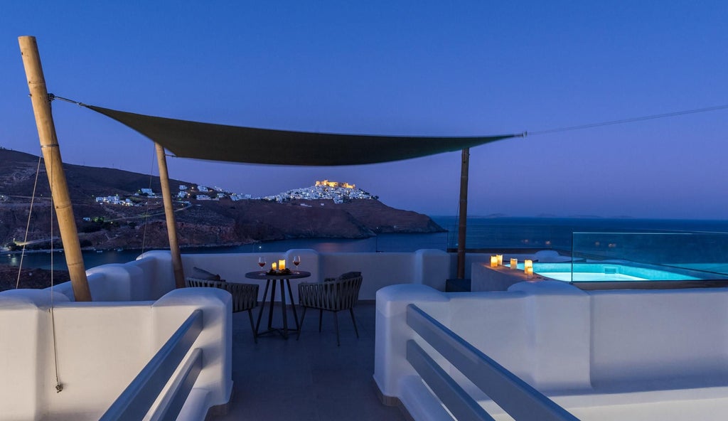 Elegant whitewashed Greek suite with blue accents, overlooking azure Aegean waters, featuring minimalist design and luxurious Mediterranean architectural details