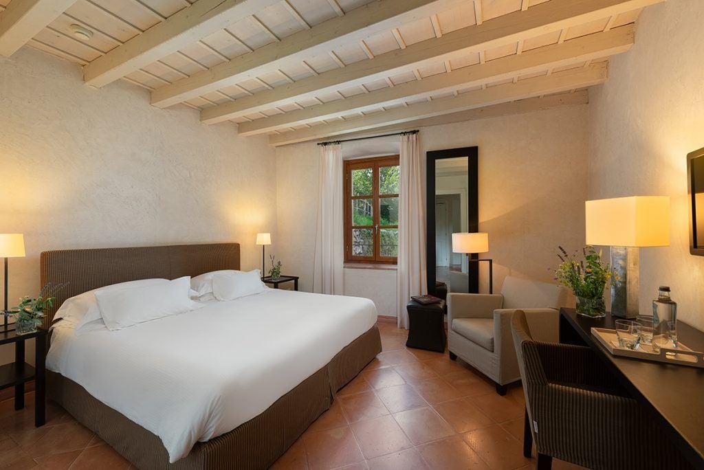 Elegant deluxe hotel room overlooking Lake Garda, with modern furnishings, soft neutral tones, and panoramic windows capturing Italian landscape