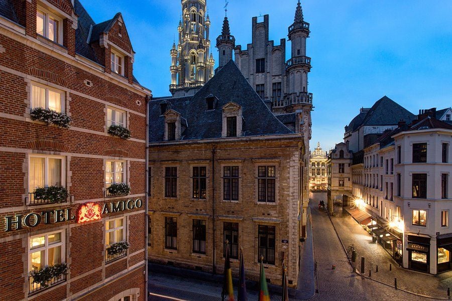 Grand limestone facade of Hotel Amigo in Brussels featuring elegant arched windows, ornate balconies and classic European architecture